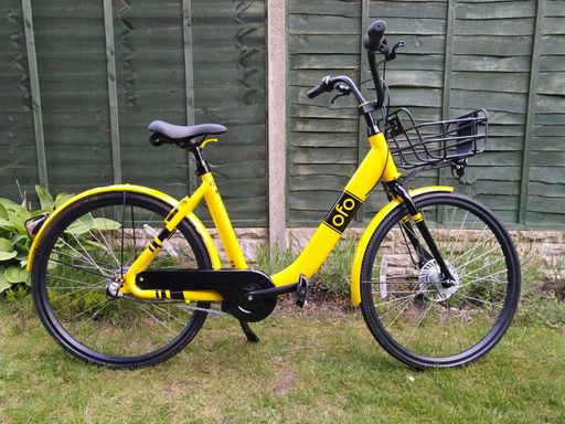 Yellow Ofo hire bike in front of fence